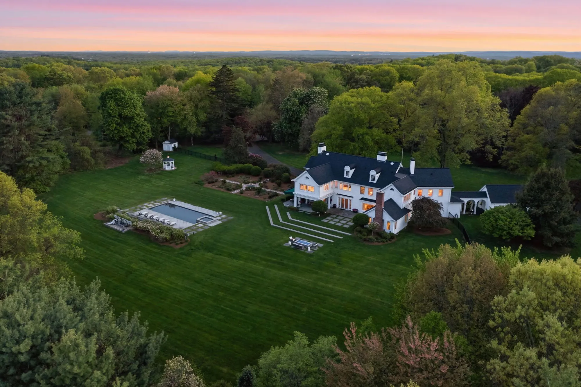 Twilight aerial of a luxury home with pool and landscaped grounds